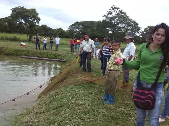 Productores junto a una laguna de cultivo de peces